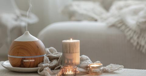 A diffuser on a tray alongside candles in a bedroom.
