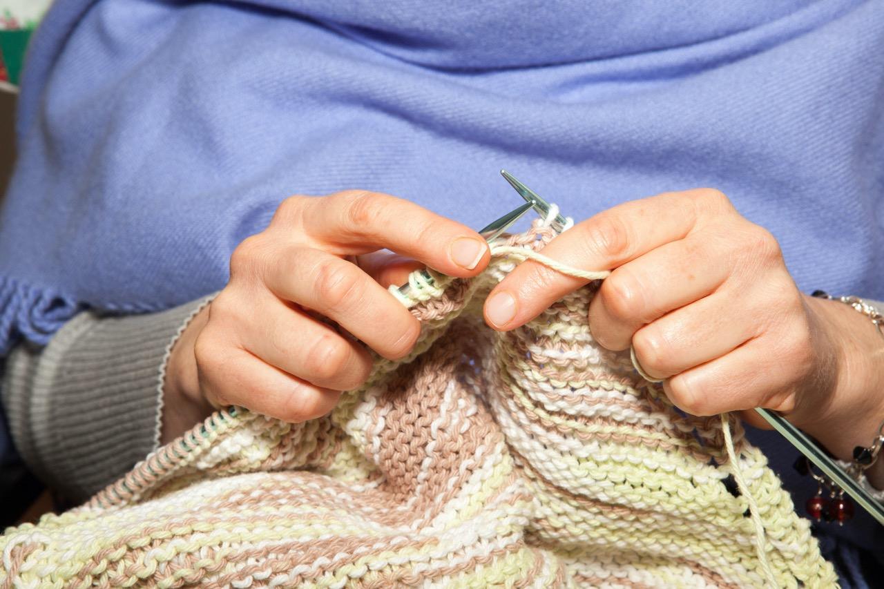 Close up of a person's hands while knitting.