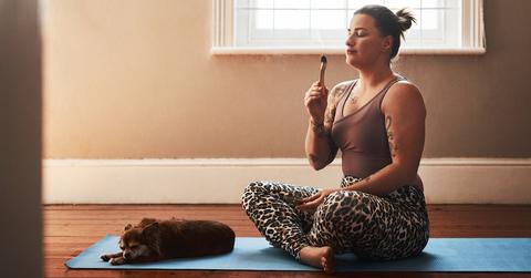 A person burning incense on a yoga mat with a dog.