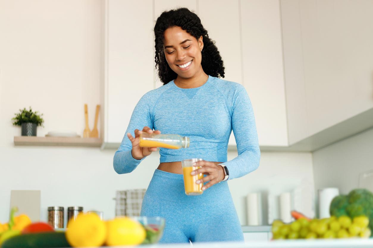 A smiling vegan athlete prepares a juiced meal in her kitchen.