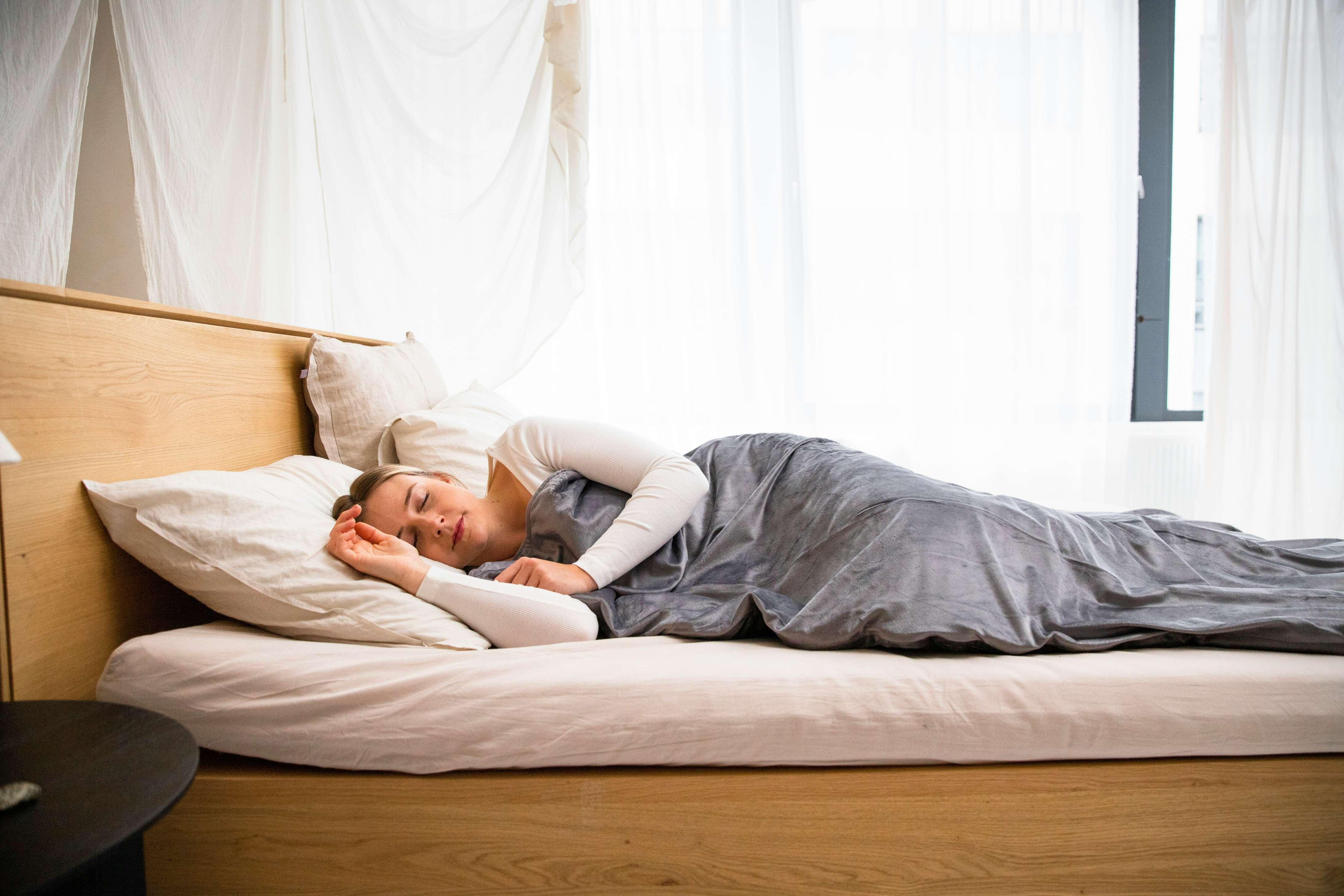 A woman appears sleeping on off-white pillows without a pillowcase.