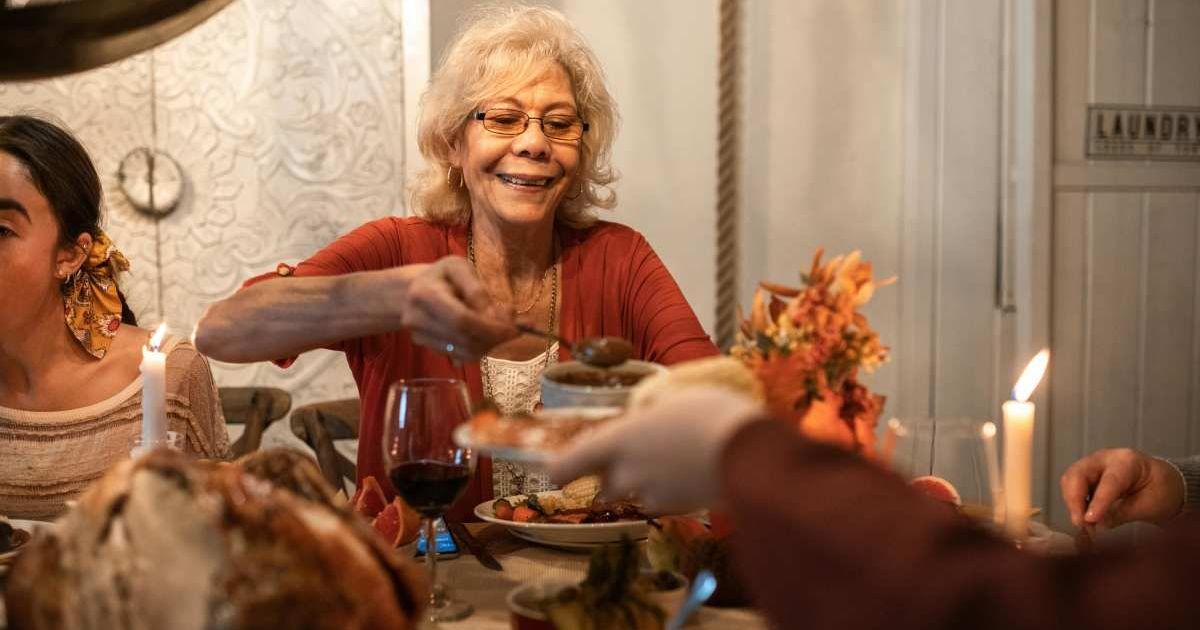 An elderly woman joyfully serving at the dinner table. (Representative Cover Image Source: Pexels | RDNE Stock project)