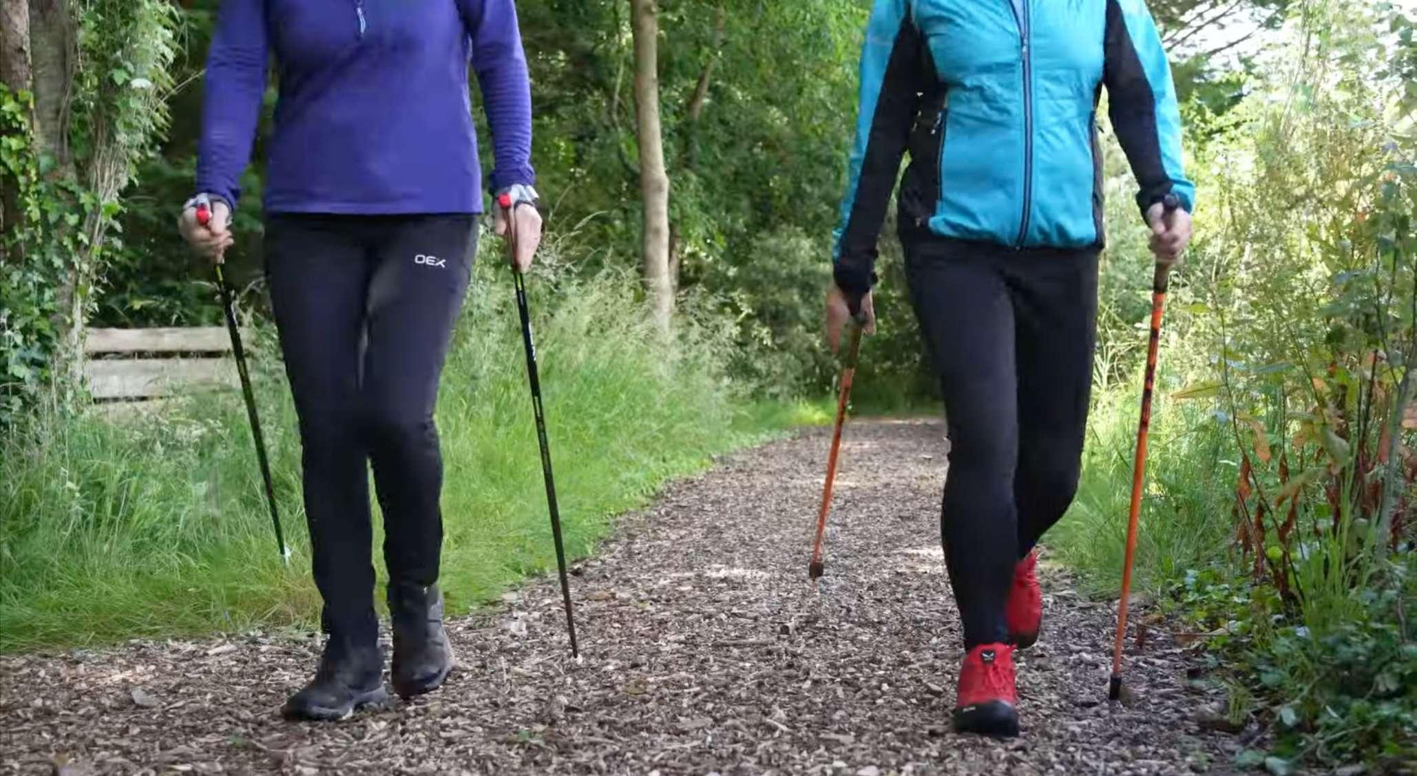 Two friends walk together using walking poles.