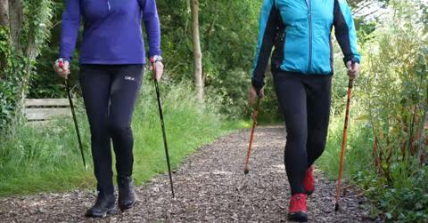 Two friends walk together using walking poles.