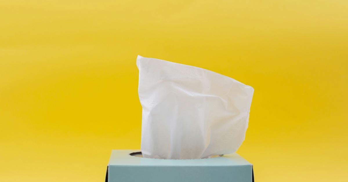 Box of tissues in a blue box with a yellow background. 