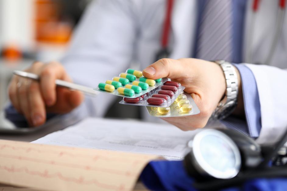 A doctor holds out three different types of medicine. 