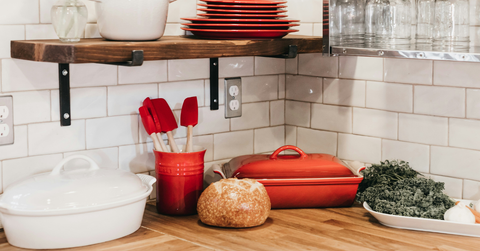 Bakeware sits atop a counter, including a set of red silicone utensils