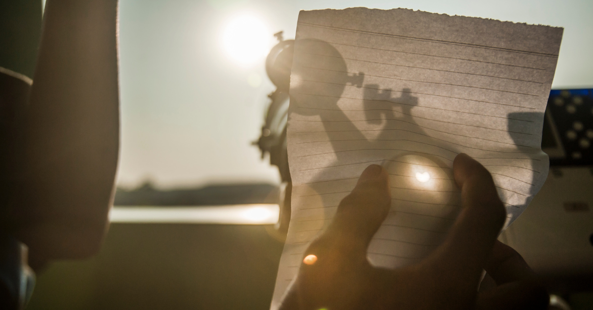 Man shows students how to capture the eclipse on a piece of paper