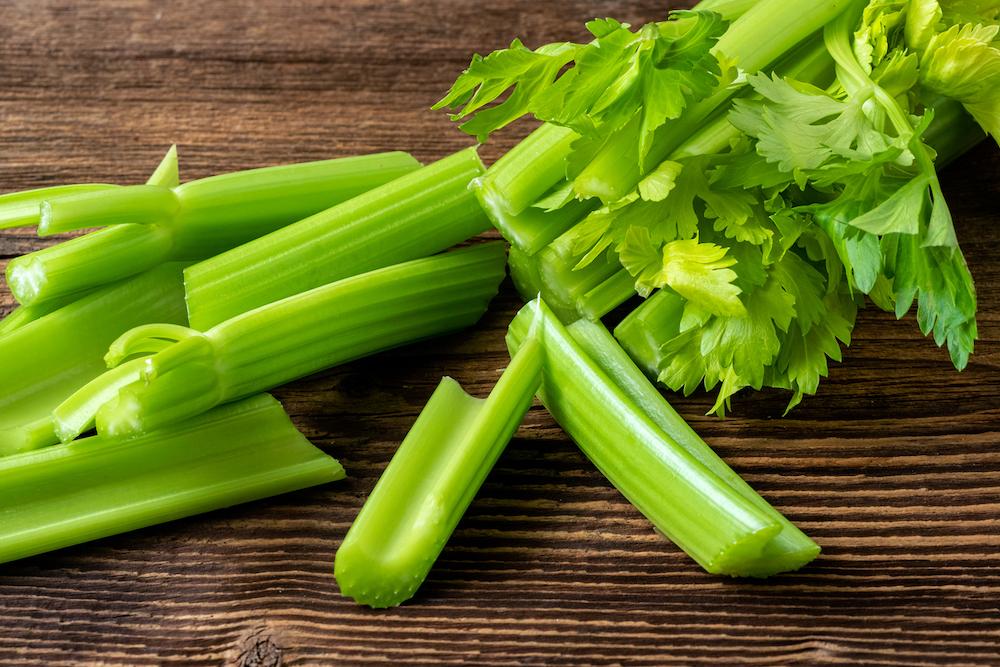 Celery stalks chopped up and placed on a wooden table. 