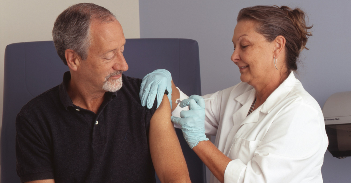 A woman gives a man a vaccine via a shot in the arm