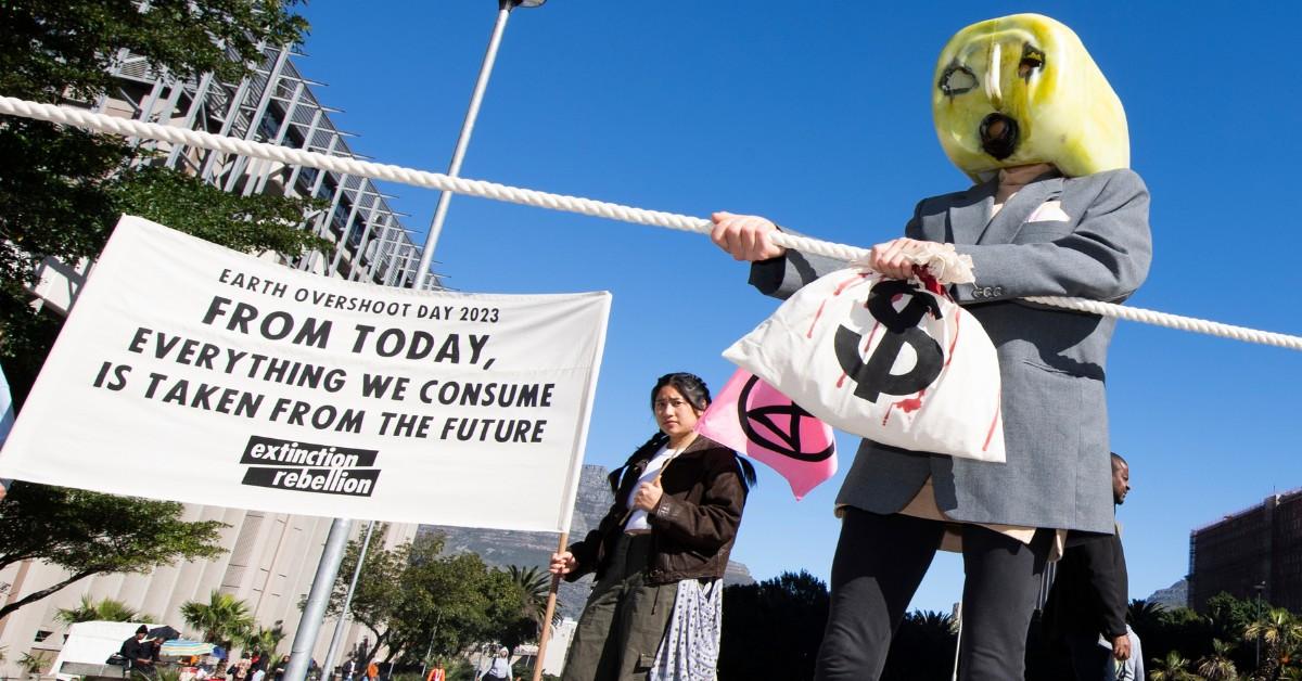 Protesters hold up a sign that says "from today, everything ew consume is taken from the future" during Earth Overshoot Day 2023