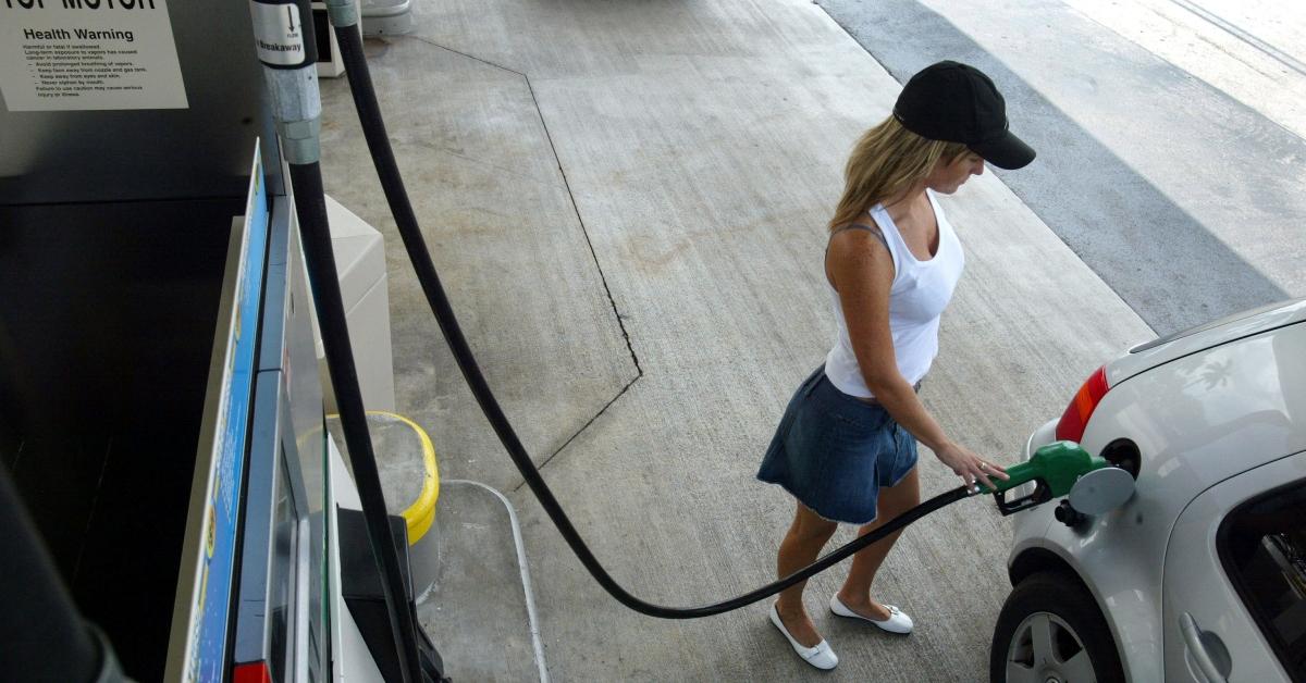 A woman gassing up her car at a gas station. 