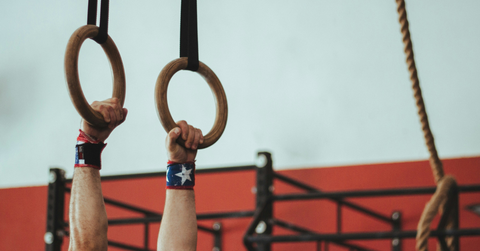 A teen in start wristbands hangs from circular rings