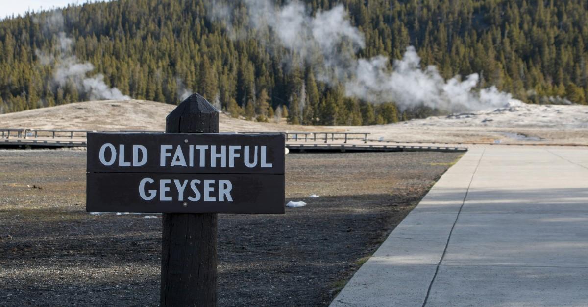 The sign for Old Faithful Geyser sits in front of the steaming geyser