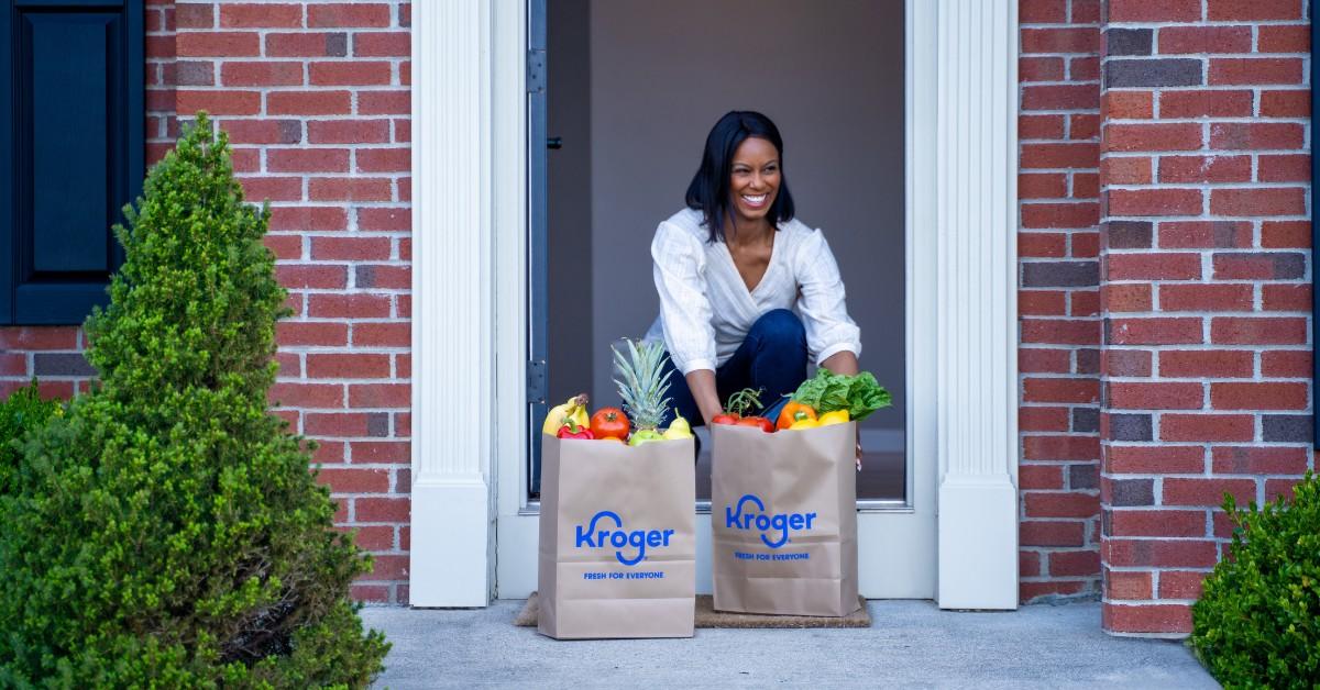 A woman picks up her Kroger bags from her front step