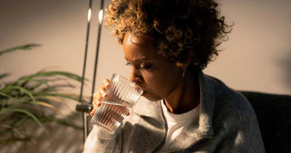 Woman concerned while drinking a glass of water at home. (Representative Cover Image Source: Pexels | Cottonbro Studios)