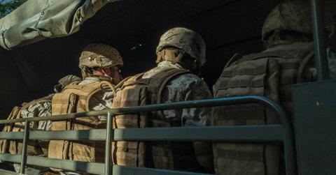Military members sit on a convoy