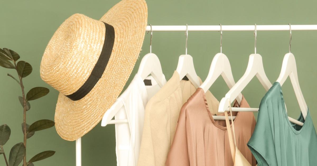 Clothes and a straw hat on a clothing rack