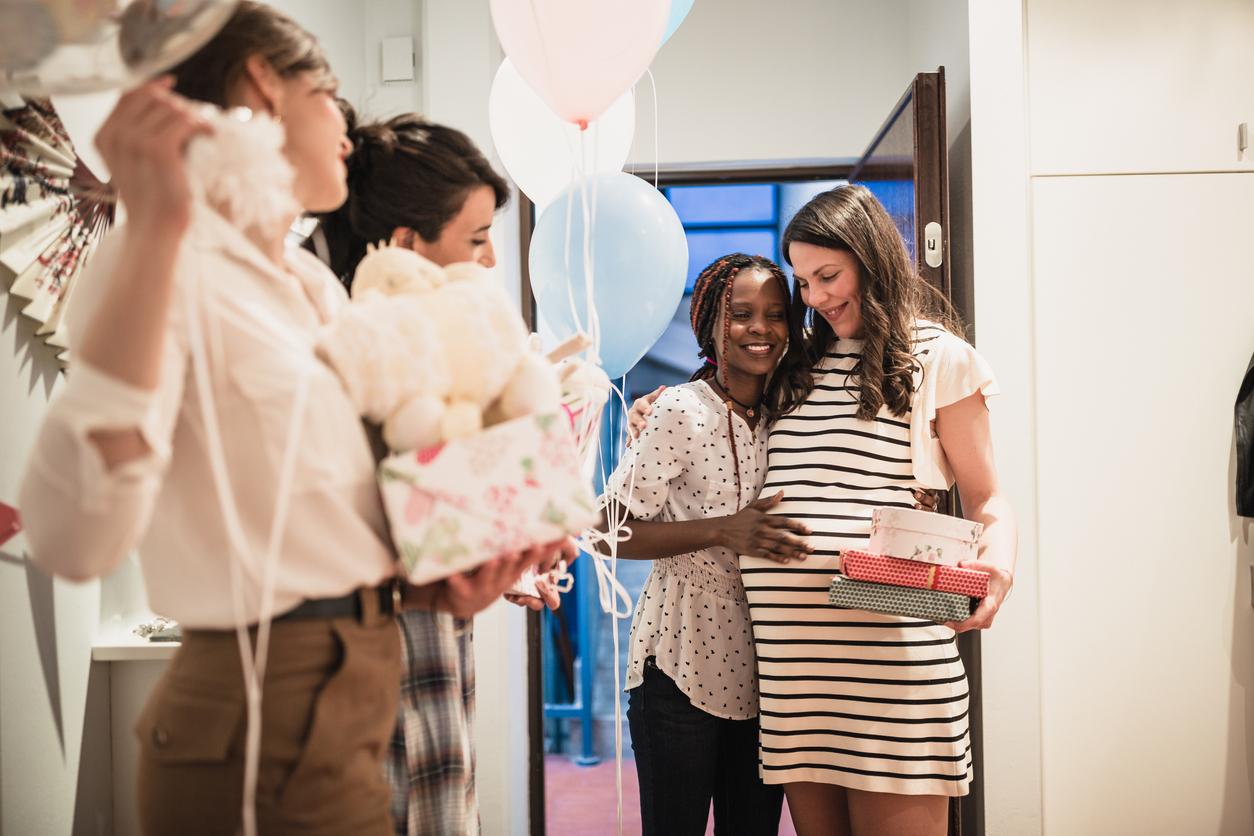 Friend giving expecting mom a gift at baby shower