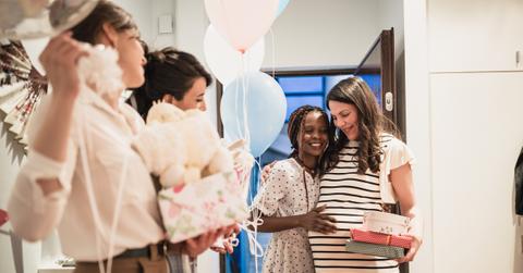 Friend giving expecting mom a gift at baby shower