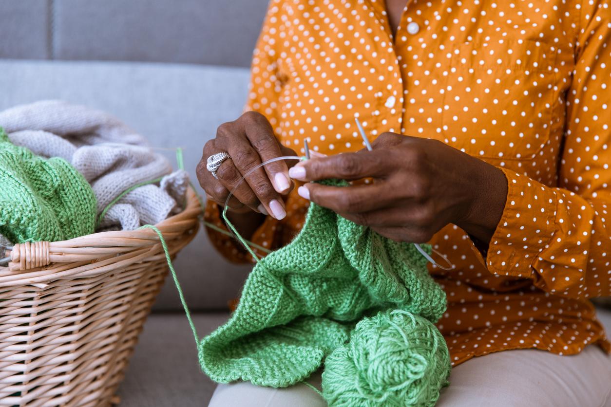 Close up of a person holding a green knitting project.