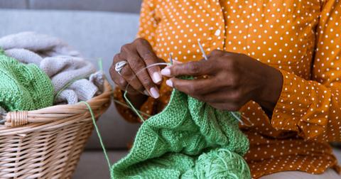 Close up of a person holding a green knitting project.
