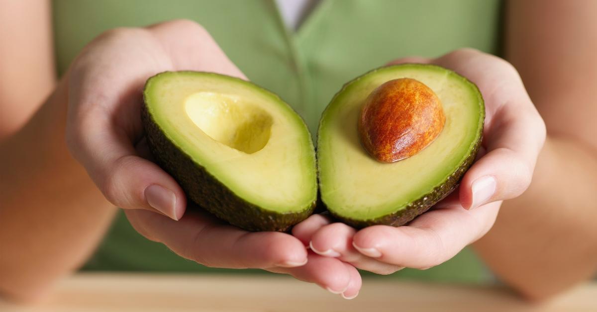 Hands holding and open avocado. 