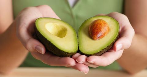 Hands holding and open avocado.