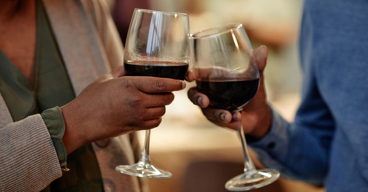 Two people clinking their glasses of red wine together. 