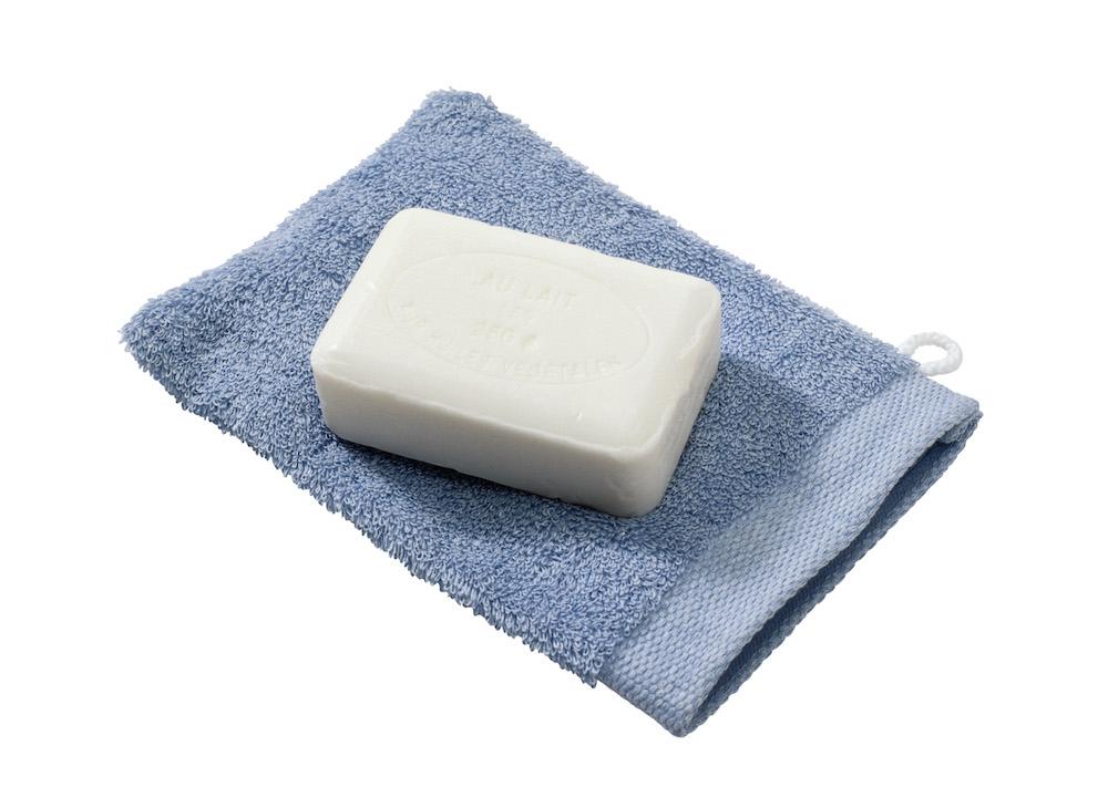 A bar of white soap on top of a blue washcloth. 