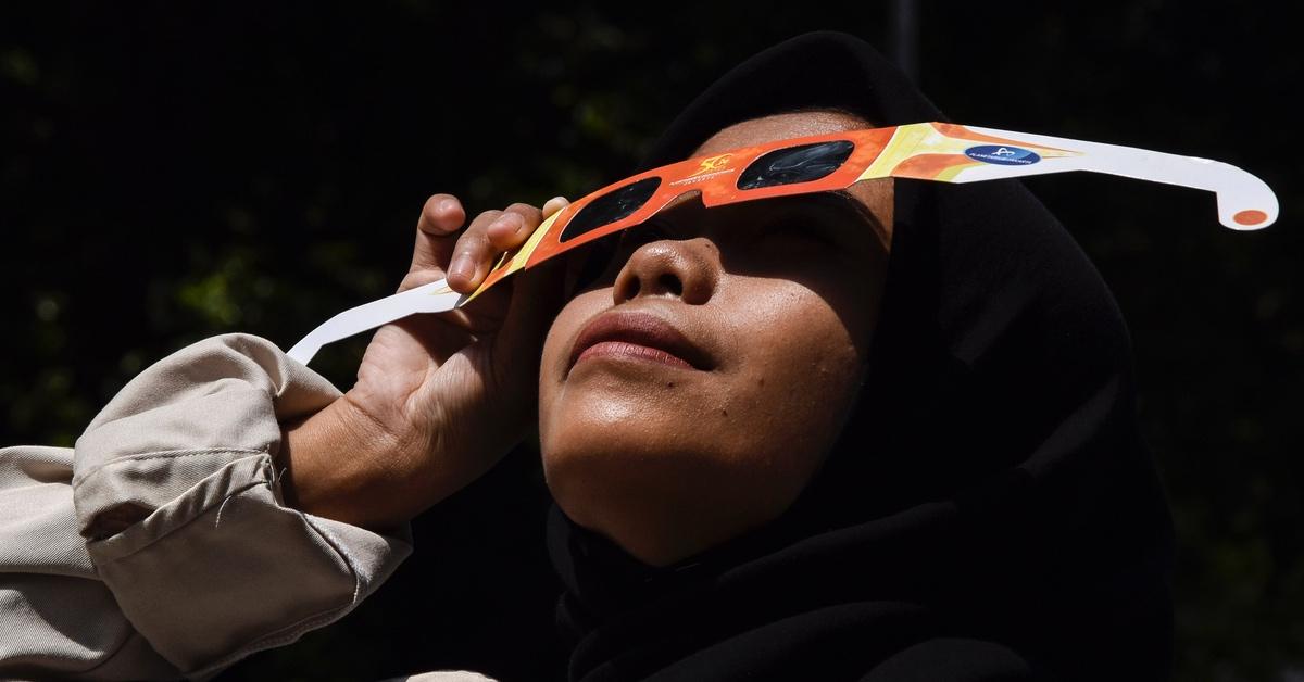 Young woman wearing solar eclipse glasses. 