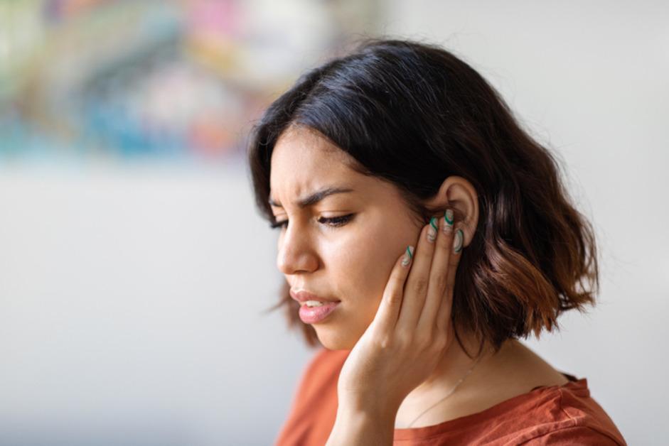 Stock photo of woman holding ear. 