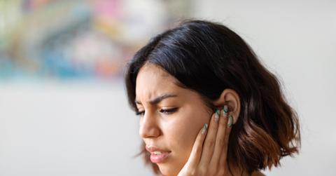 Stock photo of woman holding ear.