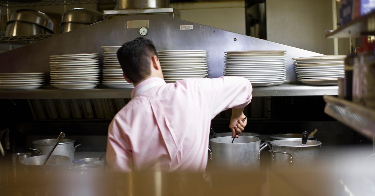 Chef stirs a pot in a commercial kitchen