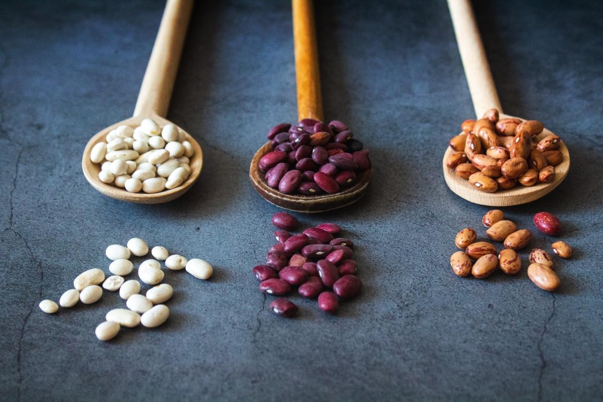 three colors of beans in wooden spoons