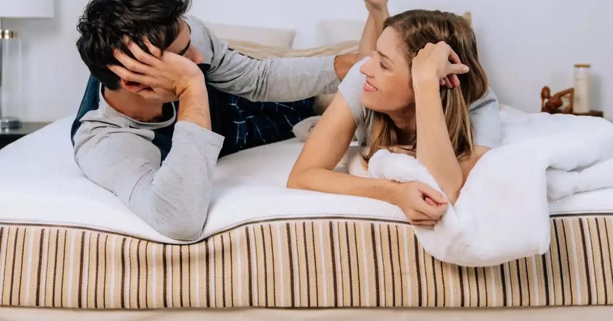 man and woman lying on a striped mattress