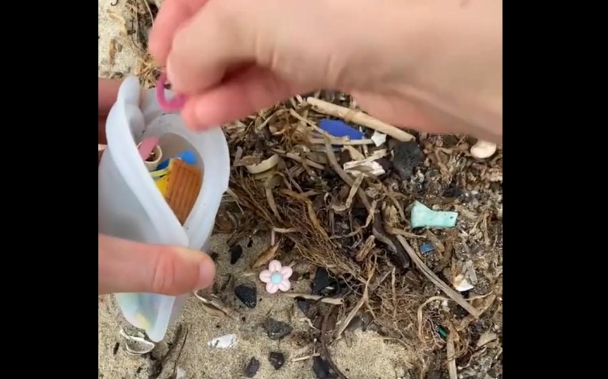 person picking up plastic from beach