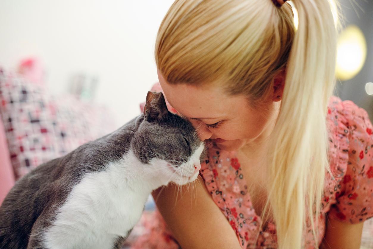 A smiling cat nuzzles his head against his smiling human companion.