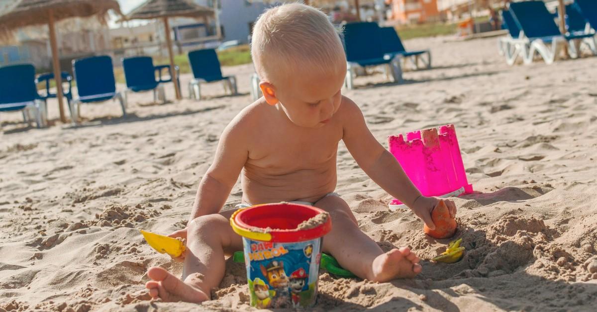 A little boy fills a bucket with sand on the beach