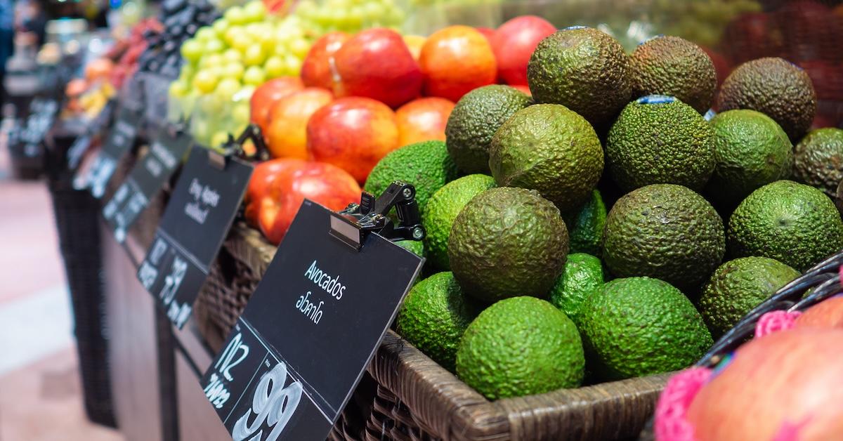 Avocados in the foreground and other fruits in the background, on sale at a supermarket