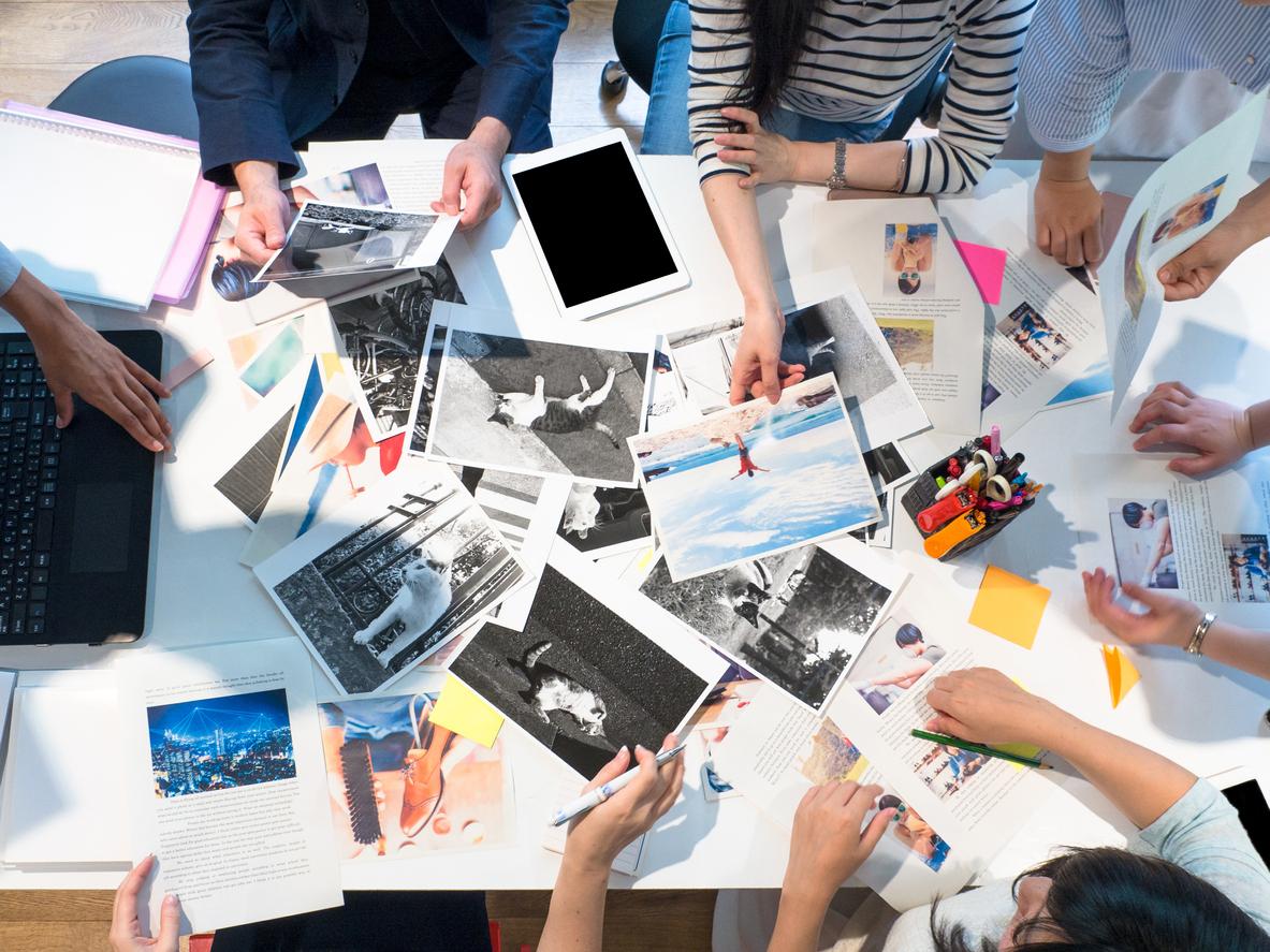 A group of people gathered around a table of printed photos.