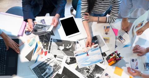 A group of people gathered around a table of printed photos.