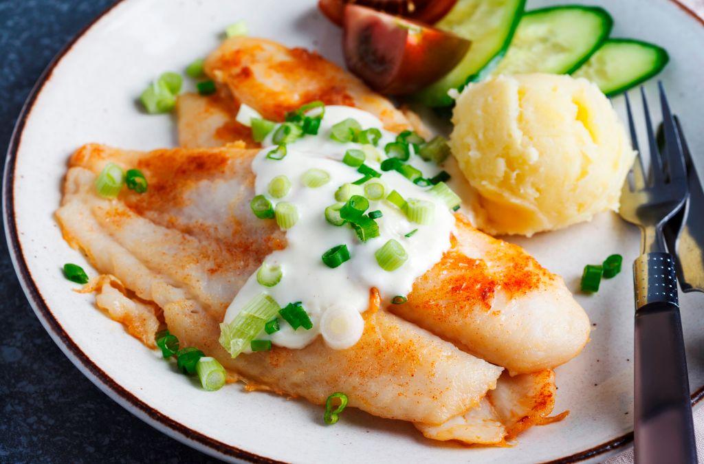 Fried swai fish with sauce. mashed potatoes, and vegetables.