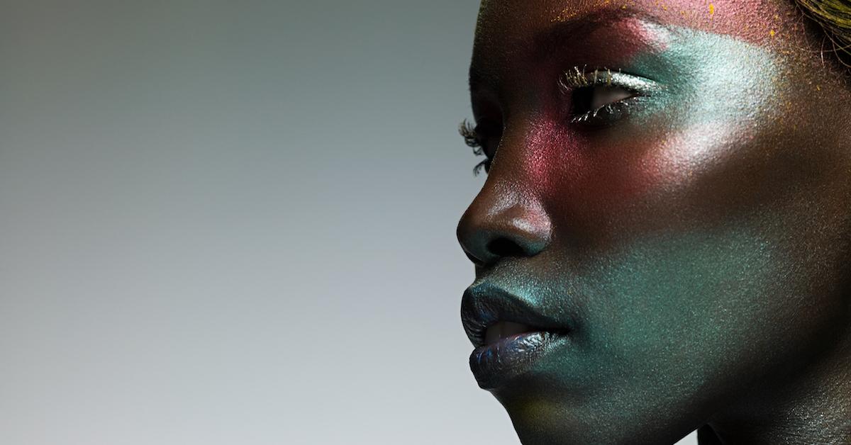 Closeup of Black woman with glittery teal face makeup