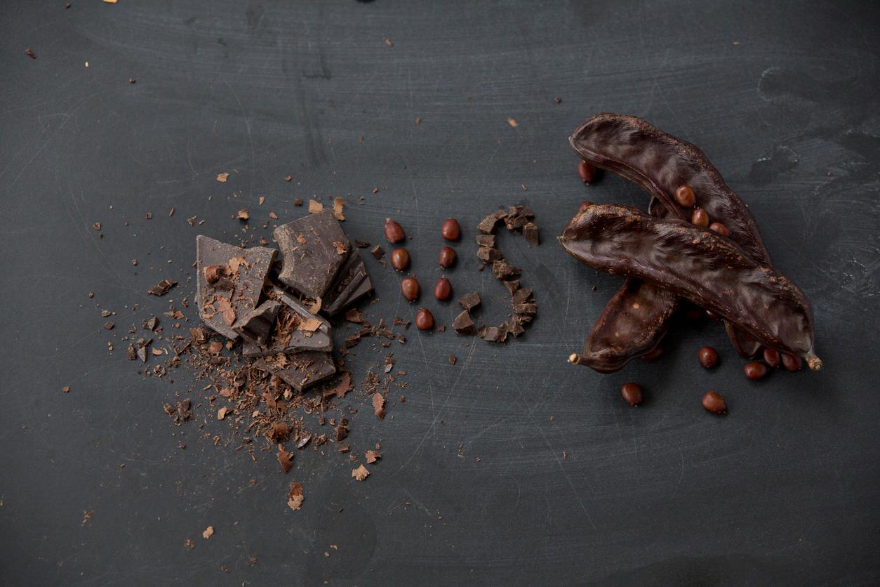 A pile of chocolate is pictured on the left, with the letters "v" and "s" in the middle and carob pods and beans on the right.