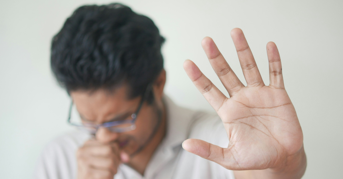 A man coughs into his hand