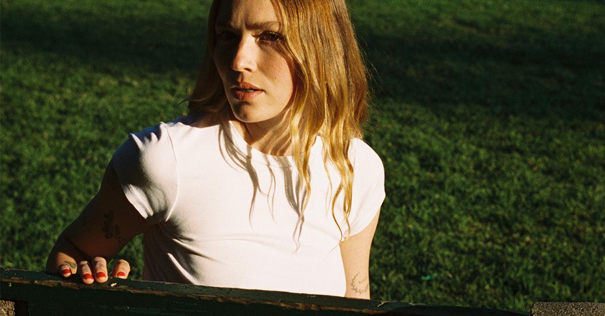 Model in white T-shirt by LA Relaxed in front of grass