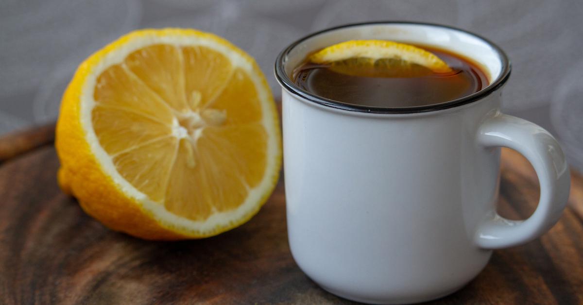 A cup of coffee next to half a lemon.