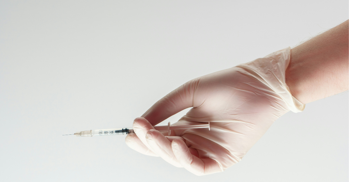 A gloved hand holds a syringe 