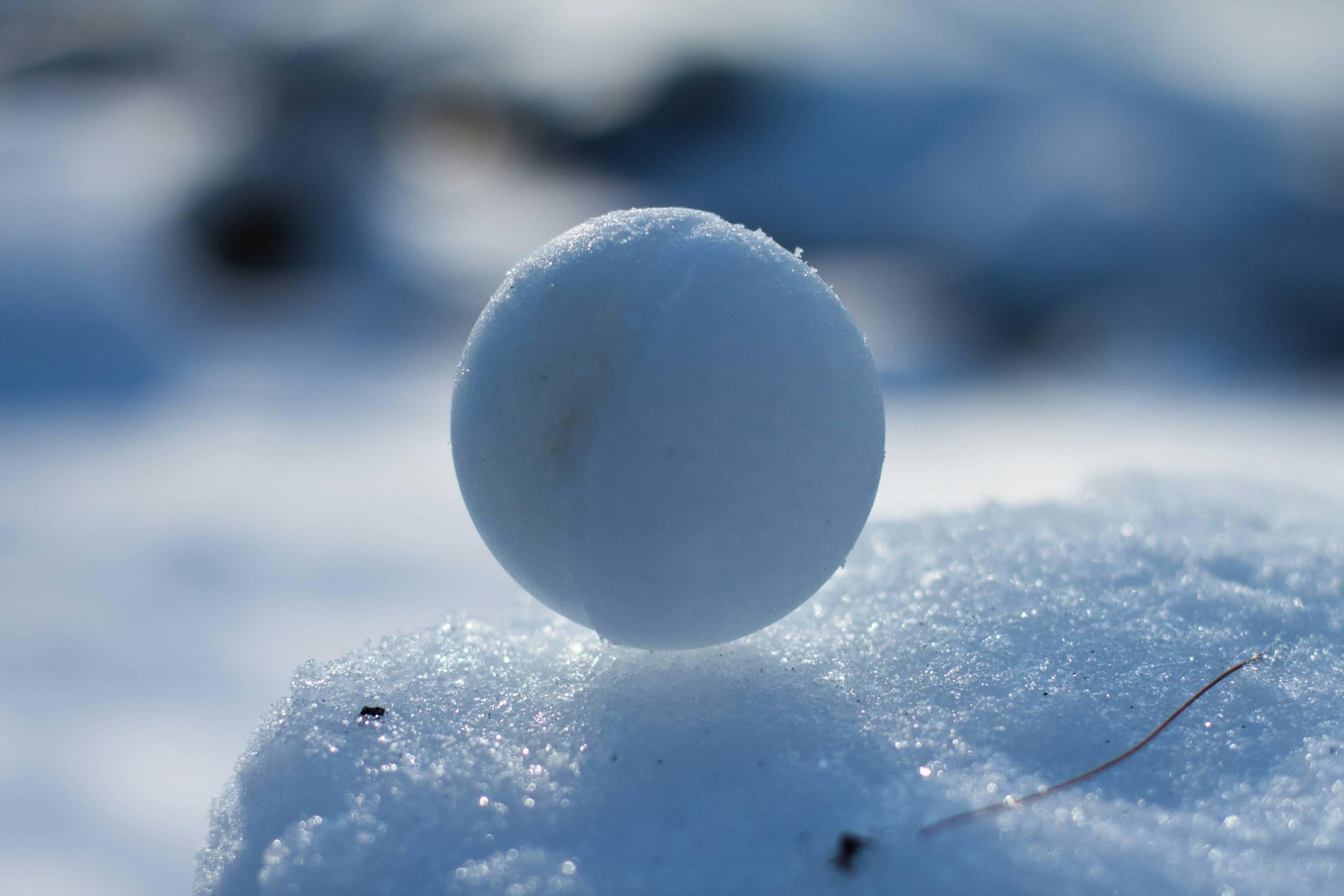A round snowball is pictured atop a block of snow.